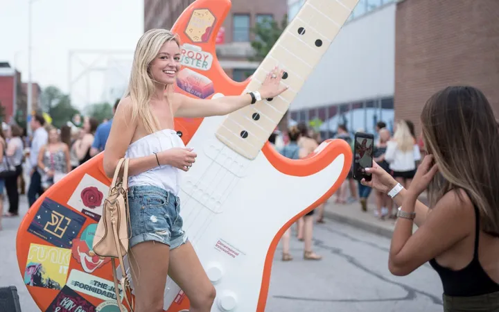 A festival attendee playing a giant illuminated electric guitar