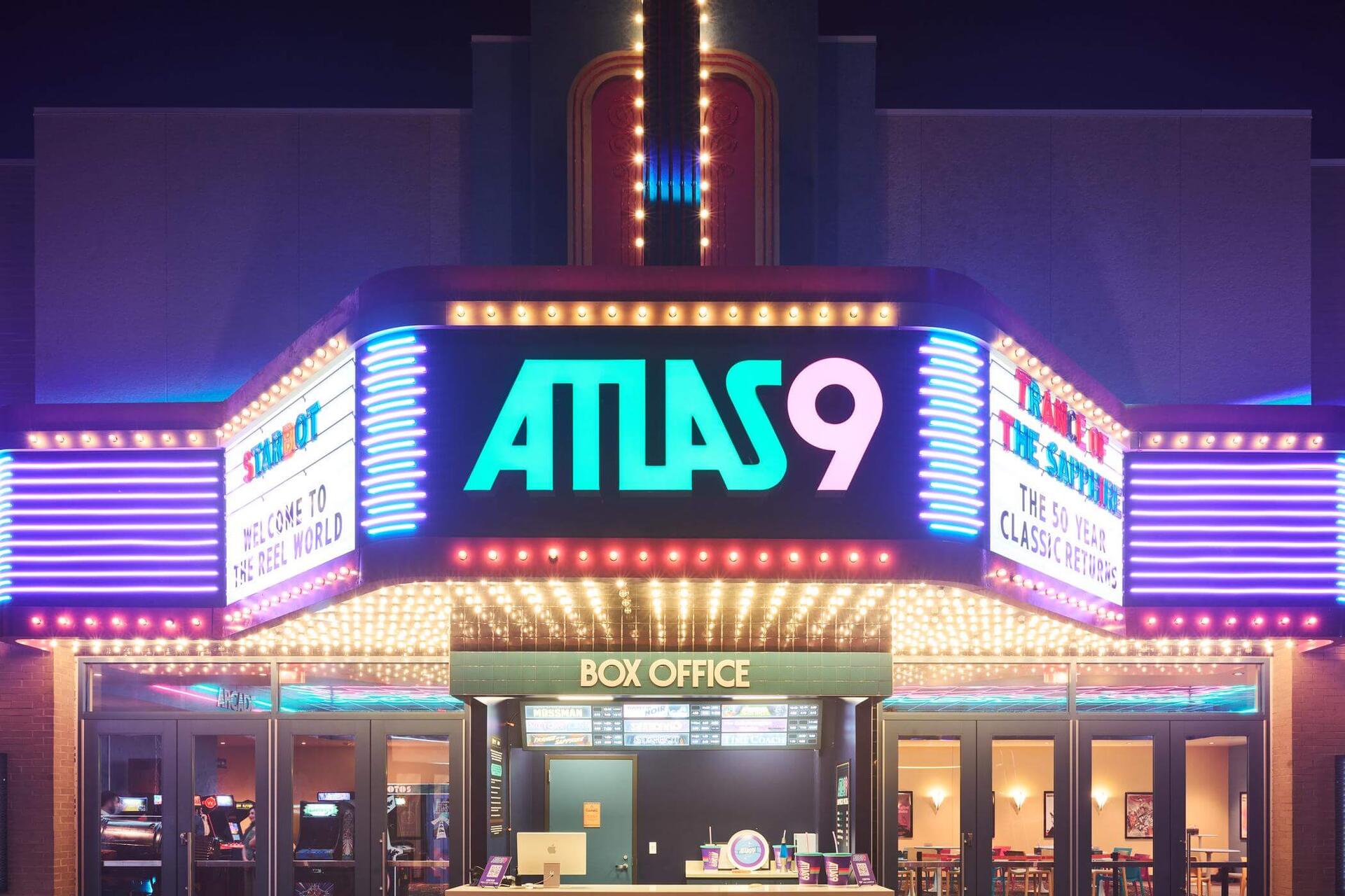 The Atlas9 marquee glowing at night, framed by colorful neon and rows of chasing bulbs above the box office