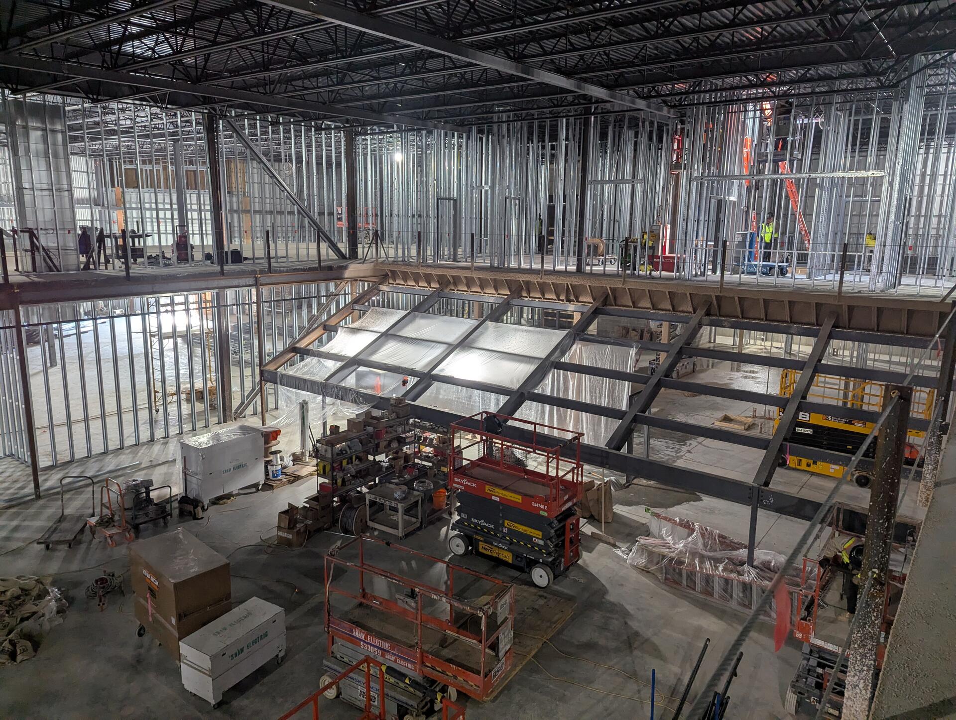 The venue under construction, with steel framing and lifts on the open floor below a mezzanine