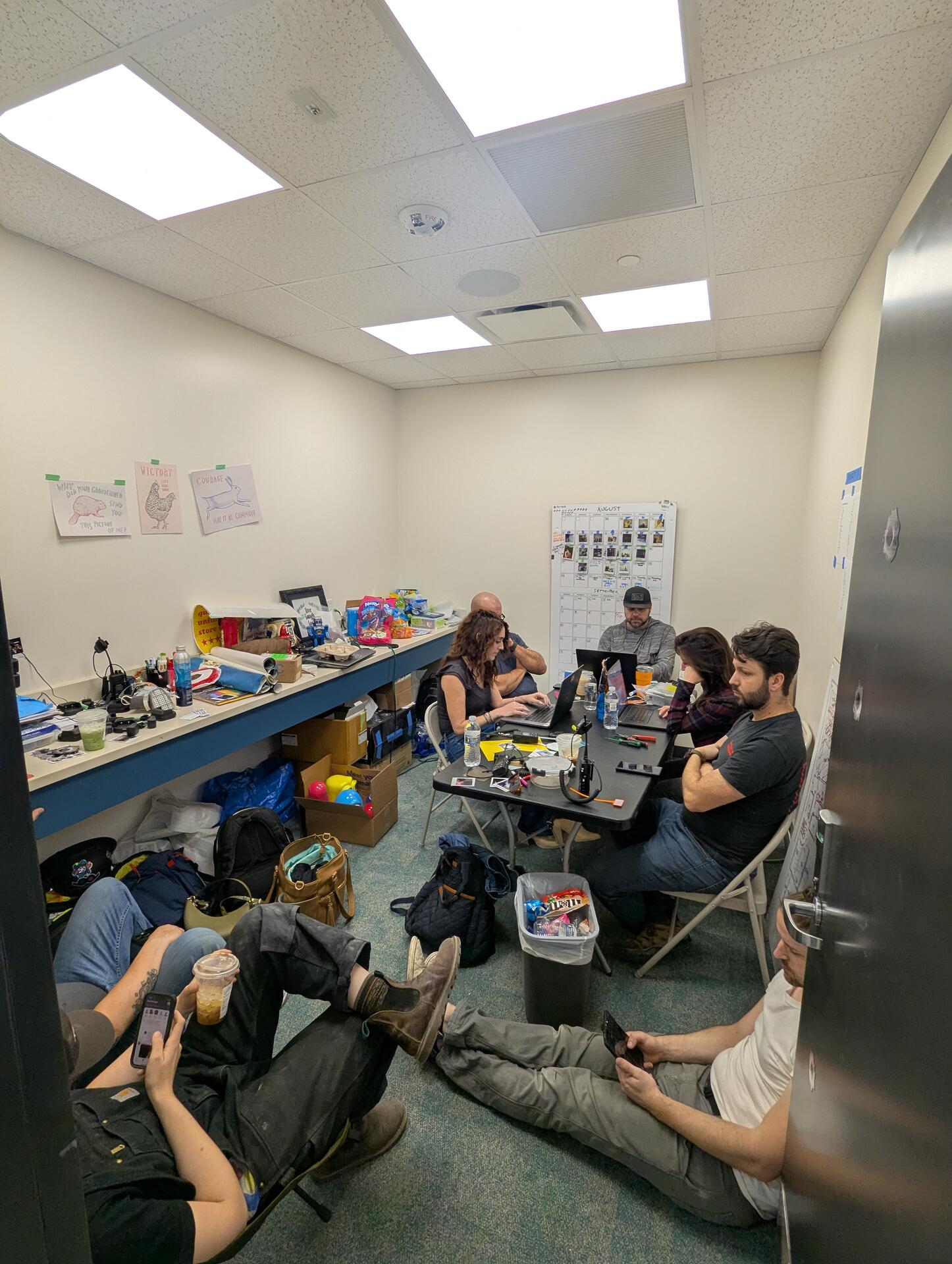The crew gathered in a small backstage room surrounded by gear and props